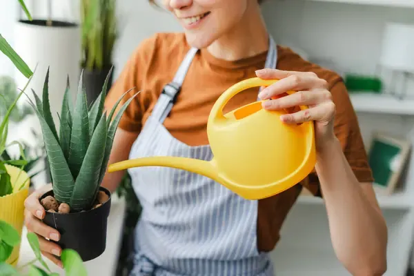 Joven regando sus plantas llevando un estilo de vida sostenible