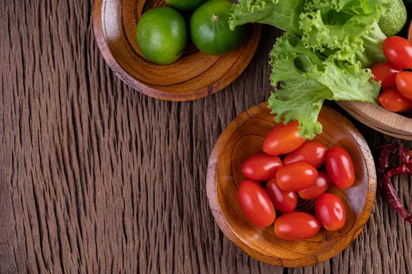 Limones, lechuga y tomates cherry encima de una mesa